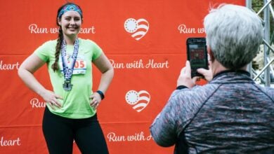 Woman posing with her medal after completing a 'Run with Heart' marathon event.