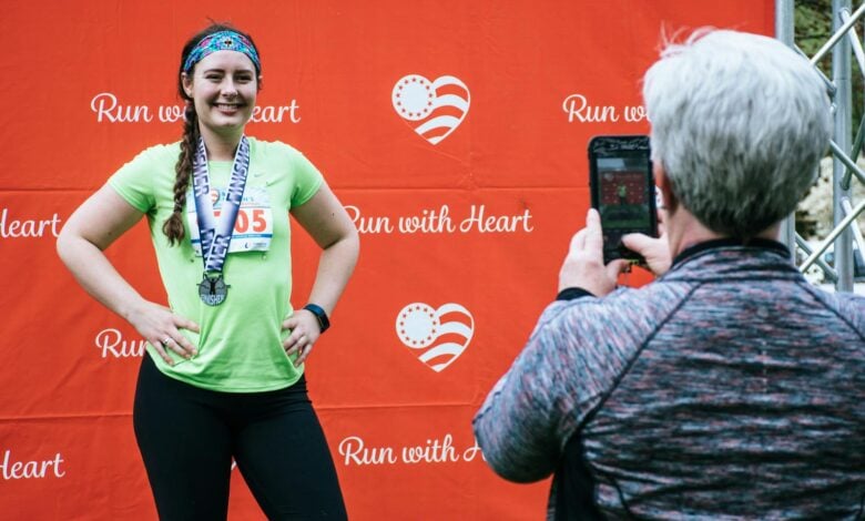 Woman posing with her medal after completing a 'Run with Heart' marathon event.