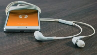 white Samsung Android smartphone turned beside white earbuds on brown board