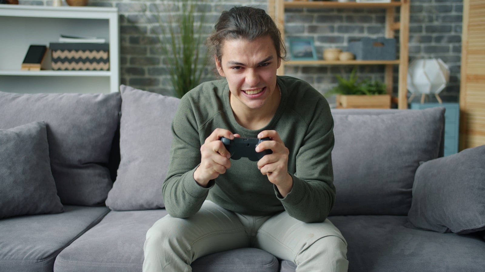 Young man intensely playing video games on couch